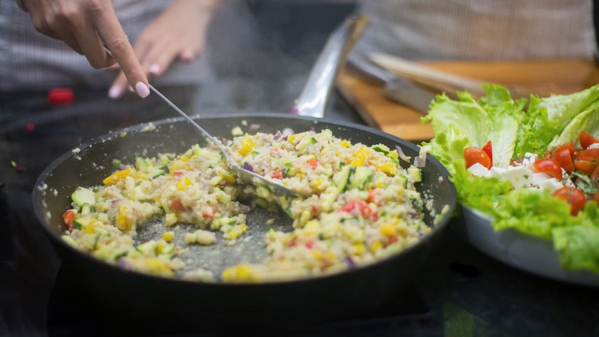 Fresh vegetable stir-fry in a pan with lettuce salad, captured in a kitchen setting.
