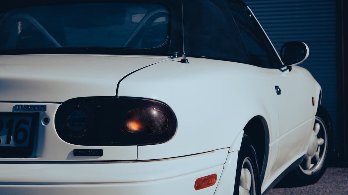 Detailed view of a classic white sports car rear in daylight, showcasing its vintage design.